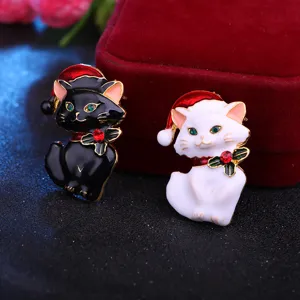 Nahaufnahme der süßen Weihnachts-Katzenbroschen mit roten Mützen, emaillierte Legierung.