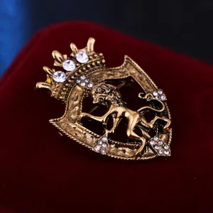 Dettaglio spilla vintage corona scudo leone con strass dorata, elegante accessorio stile regale.