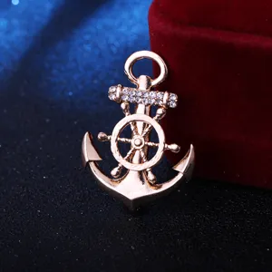 Broche ancre et roue de navire en or rose avec strass étincelants, bijou marin élégant.