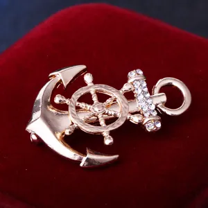 Gros plan détaillé d'une broche ancrée et roue de navire dorée, élégante épingle strass.