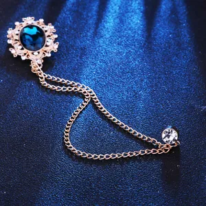 Close-up detail of vintage court style blue gemstone brooch with metallic tassel chains.