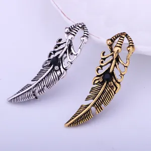 Detailed shot of vintage feather lapel pins, silver and gold finish with black center stone.
