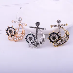 Primer plano detallado de broches nauticos de ancla y rueda con pedreria brillante.