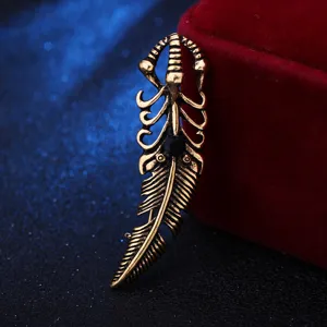 Vintage gold feather claw brooch detail view, retro metallic costume jewelry accessory.