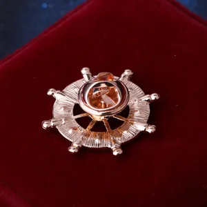 Back detail view of a rose gold ship wheel lapel pin, showing the secure metal butterfly clutch.