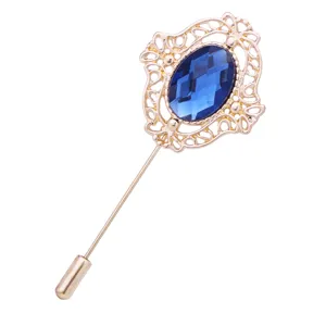 Detaillierte Nahaufnahme der goldenen filigranen Anstecknadel mit dunkelblauem Kristall.