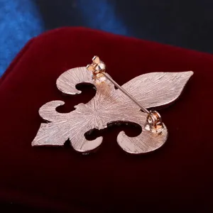 Close-up back view of gold-tone metal fleur-de-lis brooch pin with secure clasp mechanism.