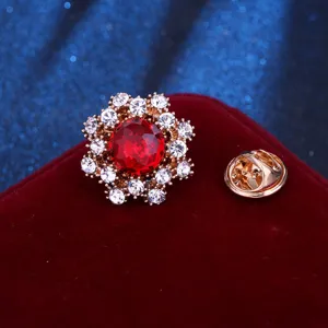 Detailed close-up of shiny rhinestone flower brooch with red crystal center and metal pin.