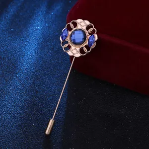 Gros plan d'une broche rétro avec des cristaux bleus et un travail de sculpture en métal doré.