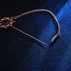 Detailed shot of a nautical ship wheel lapel pin with chain and long pin for men suits.