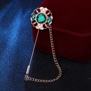 Broche épingle de revers vintage en pierre verte pour costume avec détail chaîne pompon métal.