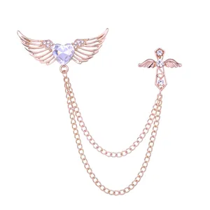 Broche de cruz de corazón de alas de ángel en tono oro rosa con pedrería transparente brillante.