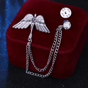 Primer plano detallado de un broche con alas de ángel de strass plateado y doble cadena.