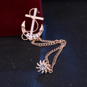 Primer plano detallado de un broche dorado de ancla y sol decorado con pedrería brillante.