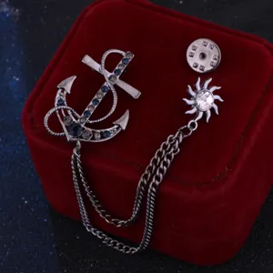 Exquisita broche de cadena con borla y ancla con pedrería brillante, detalle de accesorio.