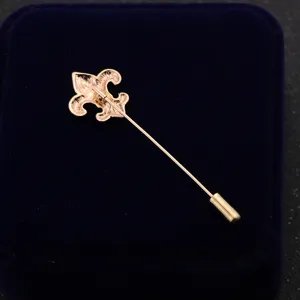 Detailed view of the rose gold fleur-de-lis lapel pin on dark blue velvet box detail shot.