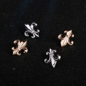 Metallic fleur-de-lis detail shot, elegant decorative clothing accessory, silver and rose gold.