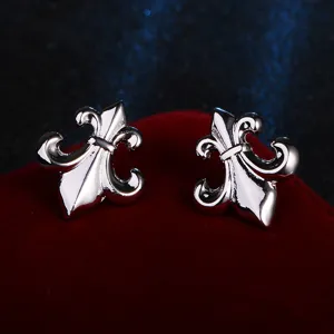 Detailed close-up of silver fleur-de-lis stud earrings displayed on red velvet.