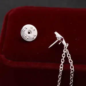 Detailed view of a stylish silver pentagram tassel brooch and collar chain for men's suits.