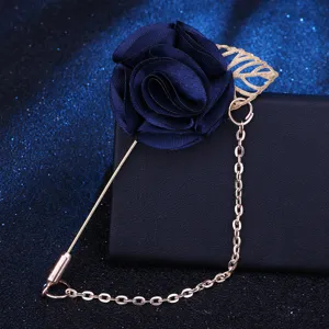 Nahaufnahme einer eleganten dunkelblauen Stoffrosen-Anstecknadel mit goldenem Blatt und Kette.