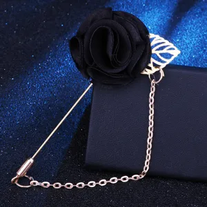 Nahaufnahme Detail der schwarzen Stoffrosen Brosche mit Goldkette und Blattausstattung.