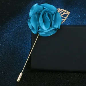 Nahaufnahme einer blauen Stoffblumen-Brosche mit goldfarbenem Blattstiel für Anzug-Revers.