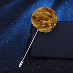 Nahaufnahme der goldenen Stoffrosen Anstecknadel mit feinen Blüten und silbernem Metallstift.