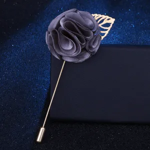 Detailansicht der grauen Stoffblumen-Brosche mit Goldblatt und langer Metallnadel.