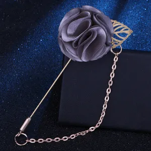 Nahaufnahme der grauen Stoffblumenbrosche mit edlem Goldblatt und feiner Metallkette.