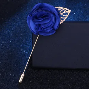 Nahaufnahme des eleganten blauen Stoffrosen-Ansteckers mit zartem goldfarbenem Blatt.