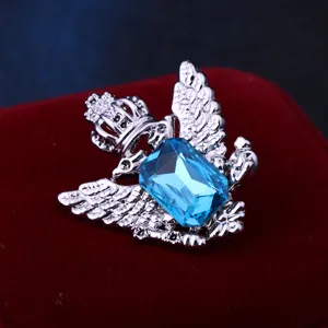Primo piano dettagliato di spilla vintage ala d'aquila con grande cristallo azzurro.