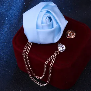 Nahaufnahme Detail der hellblauen Stoff-Rosenbroche mit Quastenkette und Strasskristall.