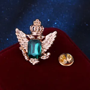 Dettaglio spilla vintage aquila con cristallo verde, accessorio per abito elegante.