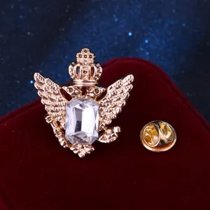 Dettaglio spilla aquila dorata vintage con strass di cristallo e corona metallica risvolto.