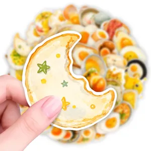 Close-up detail shot of cute watercolor moon bread sticker held in hand with sticker background.