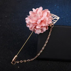 Gros plan d'une broche fleur en tissu rose avec longue épingle et chaîne dorée.