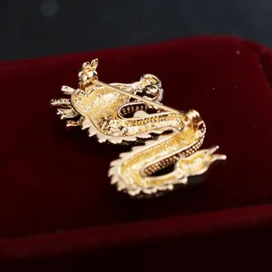 Dettaglio spilla drago color oro, accessorio di gioielleria per abito animale zodiacale.