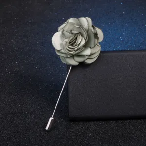 Gros plan d'une broche élégante en tissu gris en forme de fleur avec longue épingle.
