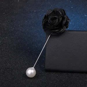 Gros plan détail de l'élégante broche longue fleur de camélia en tissu noir perle.