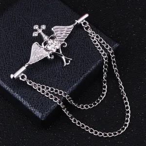Gros plan d'une broche vintage argentée ailes d'ange croix avec cristaux scintillants.