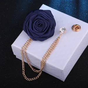 Detailaufnahme einer dunkelblauen Stoffrosenbrosche mit Goldketten und Kristalldetail.