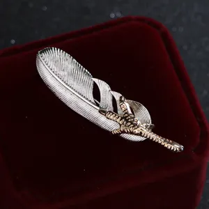 Elegant silver feather brooch with gold eagle claw design, perfect for suit coat accessories.