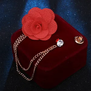 Detaillierte Nahaufnahme einer roten Stoff-Kamelien-Brosche mit goldener Quastenkette.