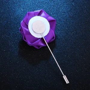 Gros plan montrant la structure de l'épingle arrière de l'accessoire de fleur en tissu violet.
