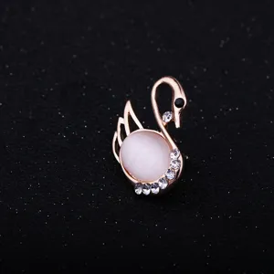 Rose gold cat eye stone swan brooch detail, elegant crystal embellished lapel pin accessory.