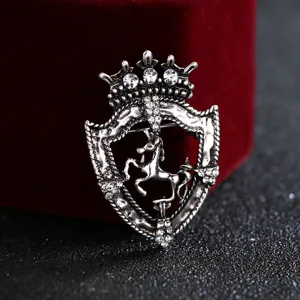 Primo piano dettagliato della spilla vintage in argento con scudo, strass e corona.