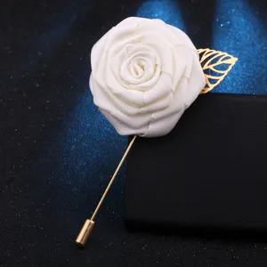 Nahaufnahme der weißen Stoffrosenbrosche mit goldenem Blatt, elegantes Accessoire für Revers.