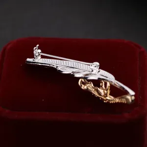 Detailed view of the elegant metal feather and eagle claw brooch, silver and gold tone.