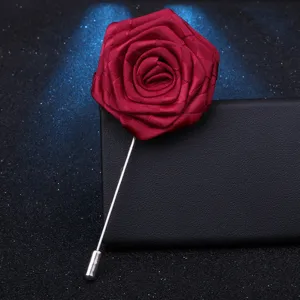 Détail en gros plan d'une broche rose en tissu rouge foncé avec longue épingle argentée.