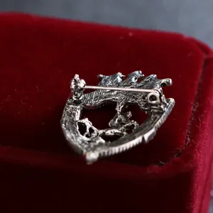 Vista dettagliata spilla cavallo scudo argento vintage, accessorio classico per abito da uomo.